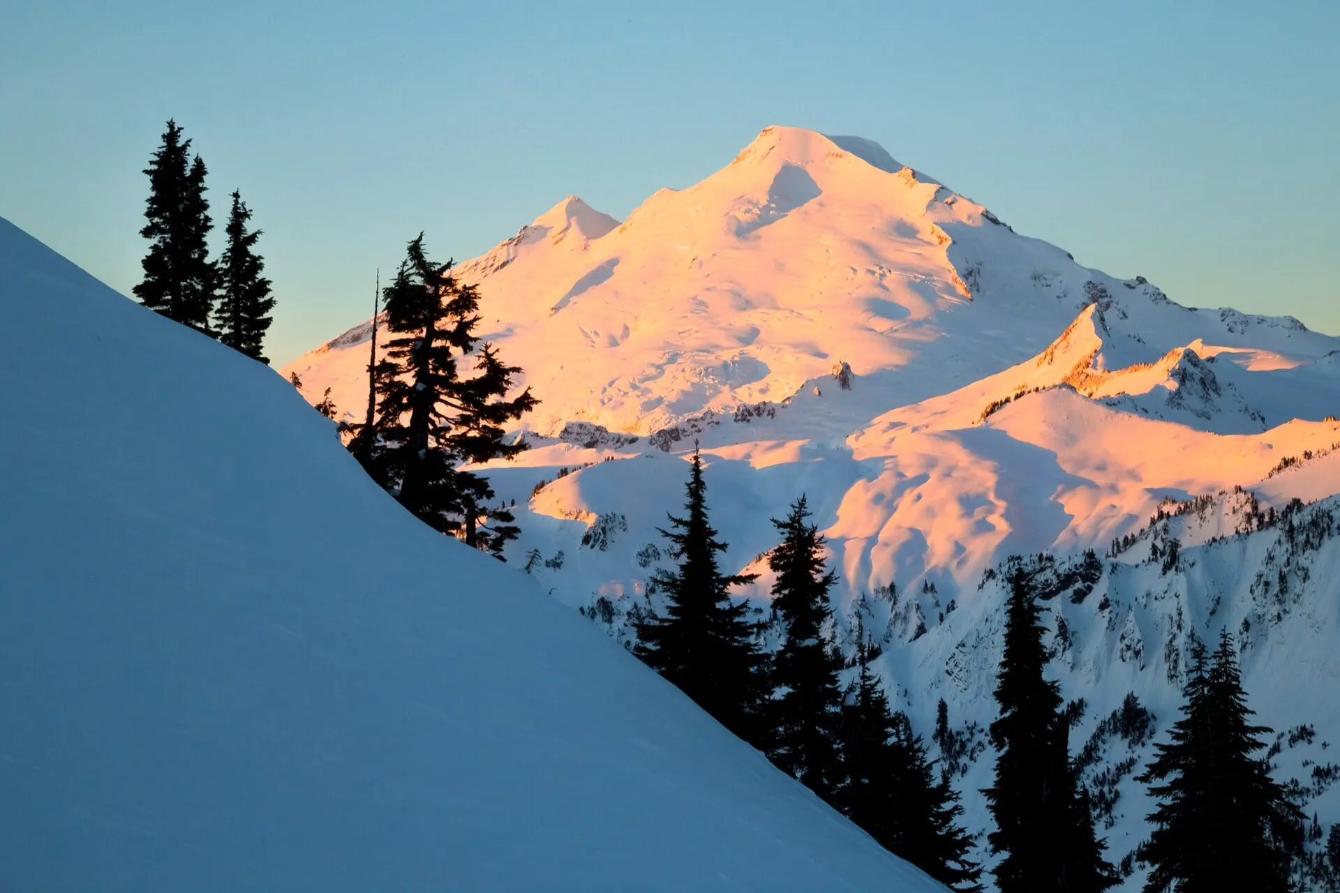 Winter alpenglow on Mount Baker above the deep snowpack the highway climbs into