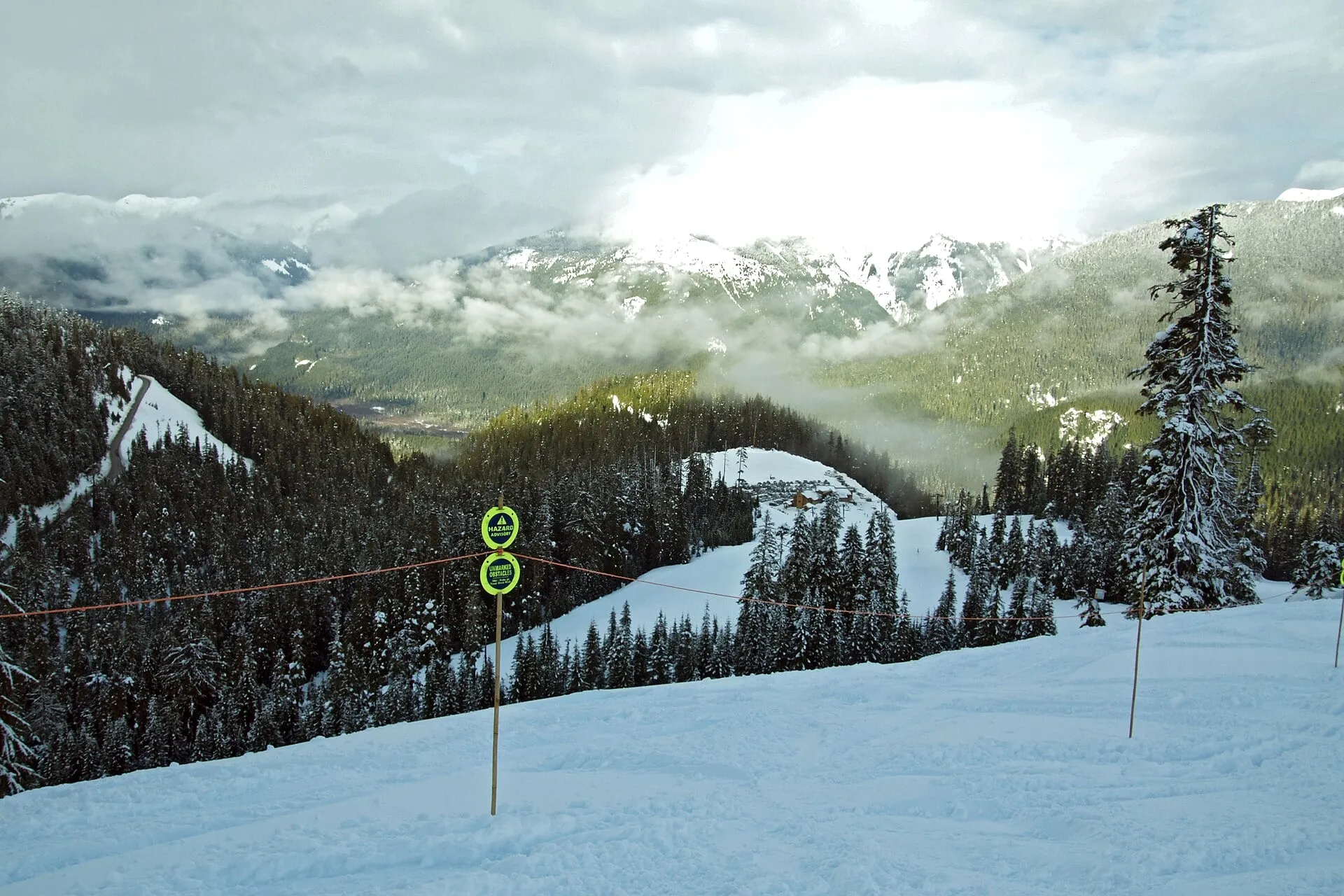 Snow-covered run at Mt. Baker Ski Area looking down the valley to the snowline and green forest below