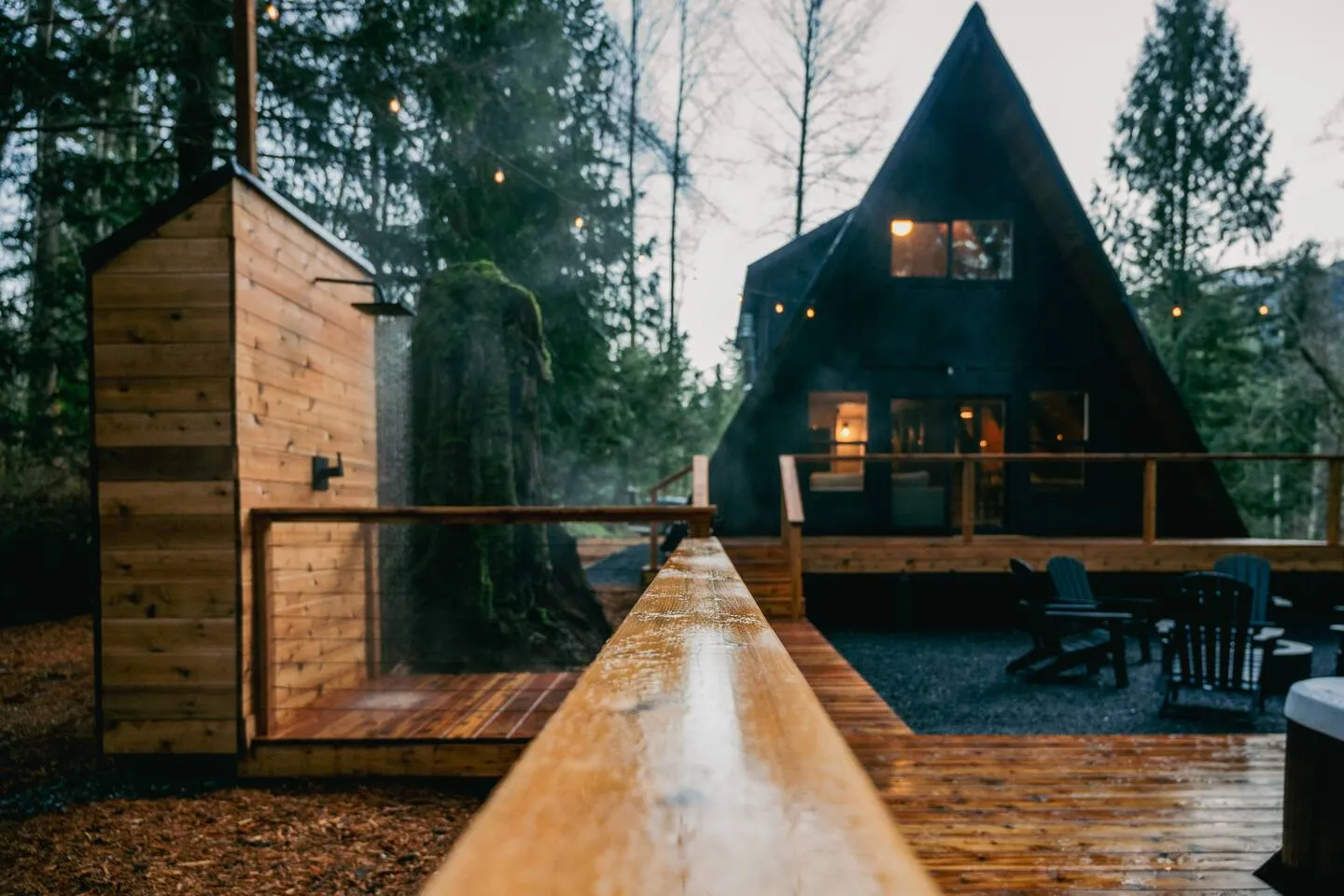 Couple relaxing in the steaming hot tub in front of the black A-frame cabin