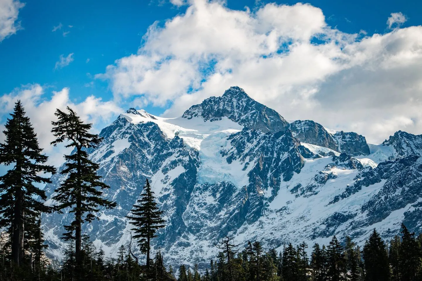 Snow-covered Mount Shuksan under a blue sky above the treeline at the top of the Mt. Baker Highway